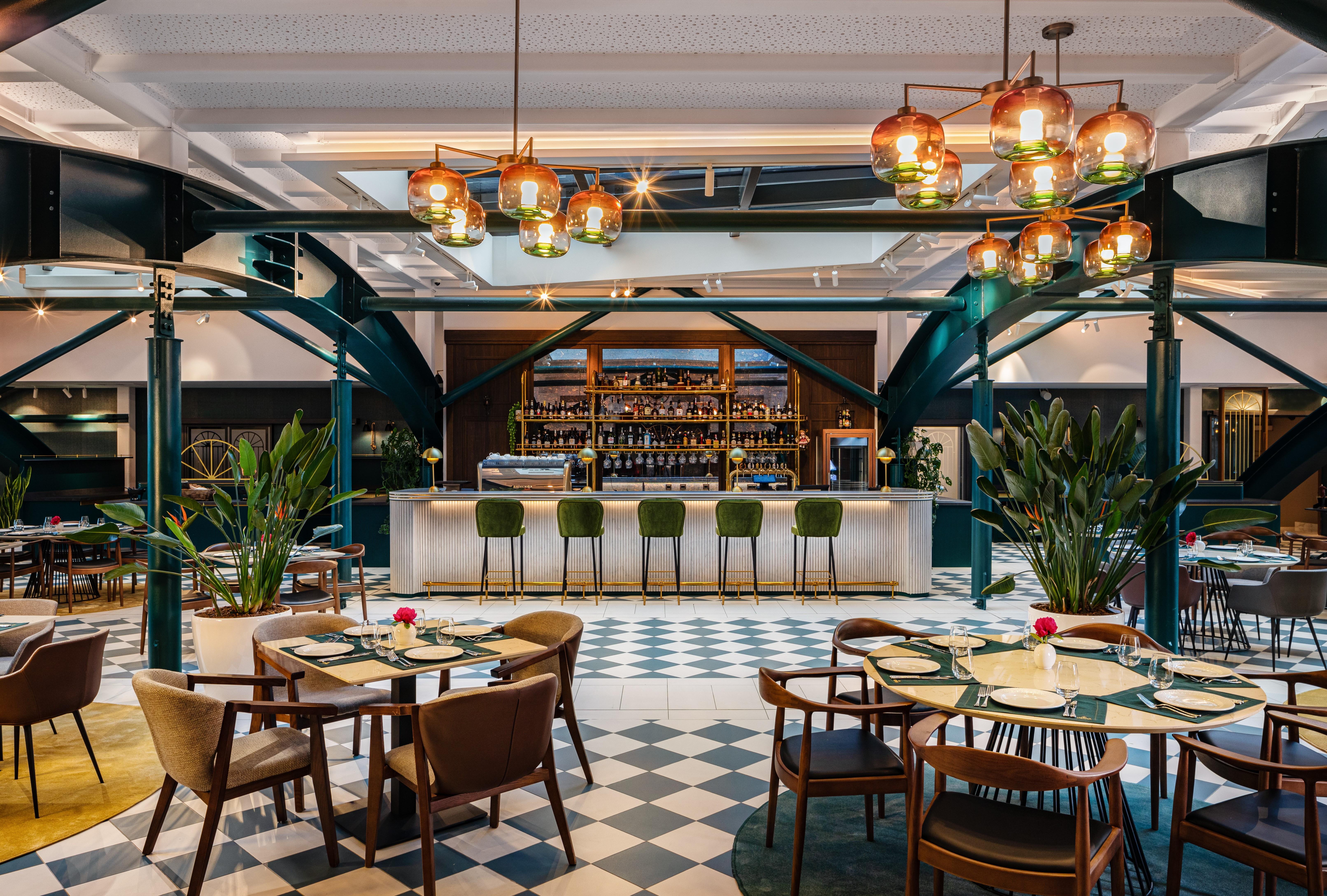 Grand Hotel Millennium Sofia Exterior photo The photo showcases a stylish restaurant interior. There are several tables set with chairs arranged around them, featuring a mix of styles. In the background, a sleek bar counter is visible, stocked with various bottles. The bar is complemented by e