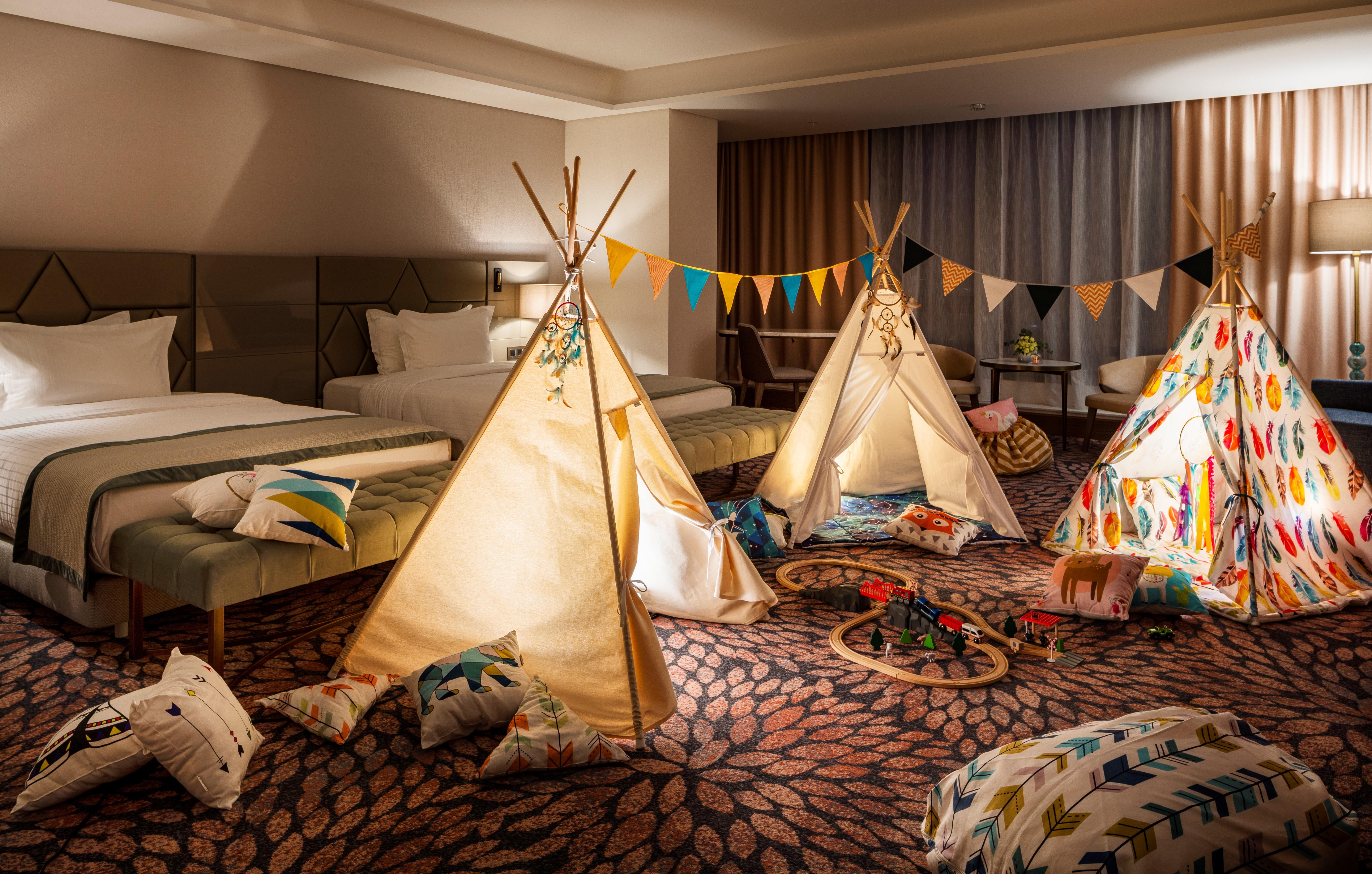 Grand Hotel Millennium Sofia Exterior photo The photo shows a cozy room featuring three children's teepees made of fabric, arranged in a playful manner. The teepees are decorated with colorful patterns and surrounded by various cushions and pillows scattered on the floor. There are also decora